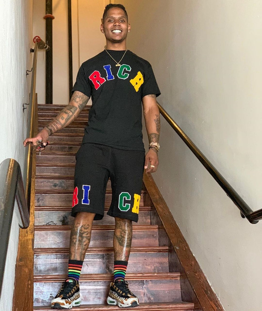 Male model wears "RICH" Tee and Shorts Set by Twenty1Rich with the multicolored "RICH" logo 